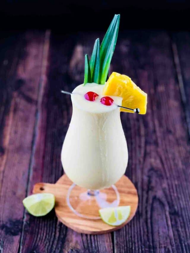 The Bacardi pina colada in a glass garnished with pineapple, cherries, and pineapple leaves.