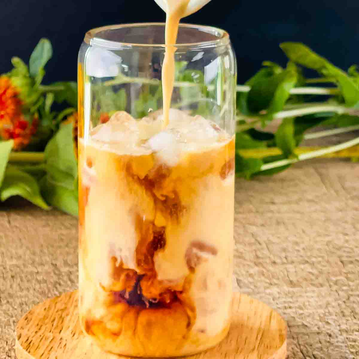 Pumpkin cream cold brew being poured into a tall glass.