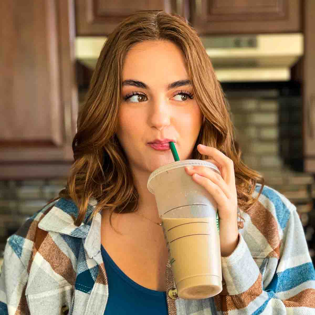 Rosie drinking on a homemade iced coffee in her kitchen.