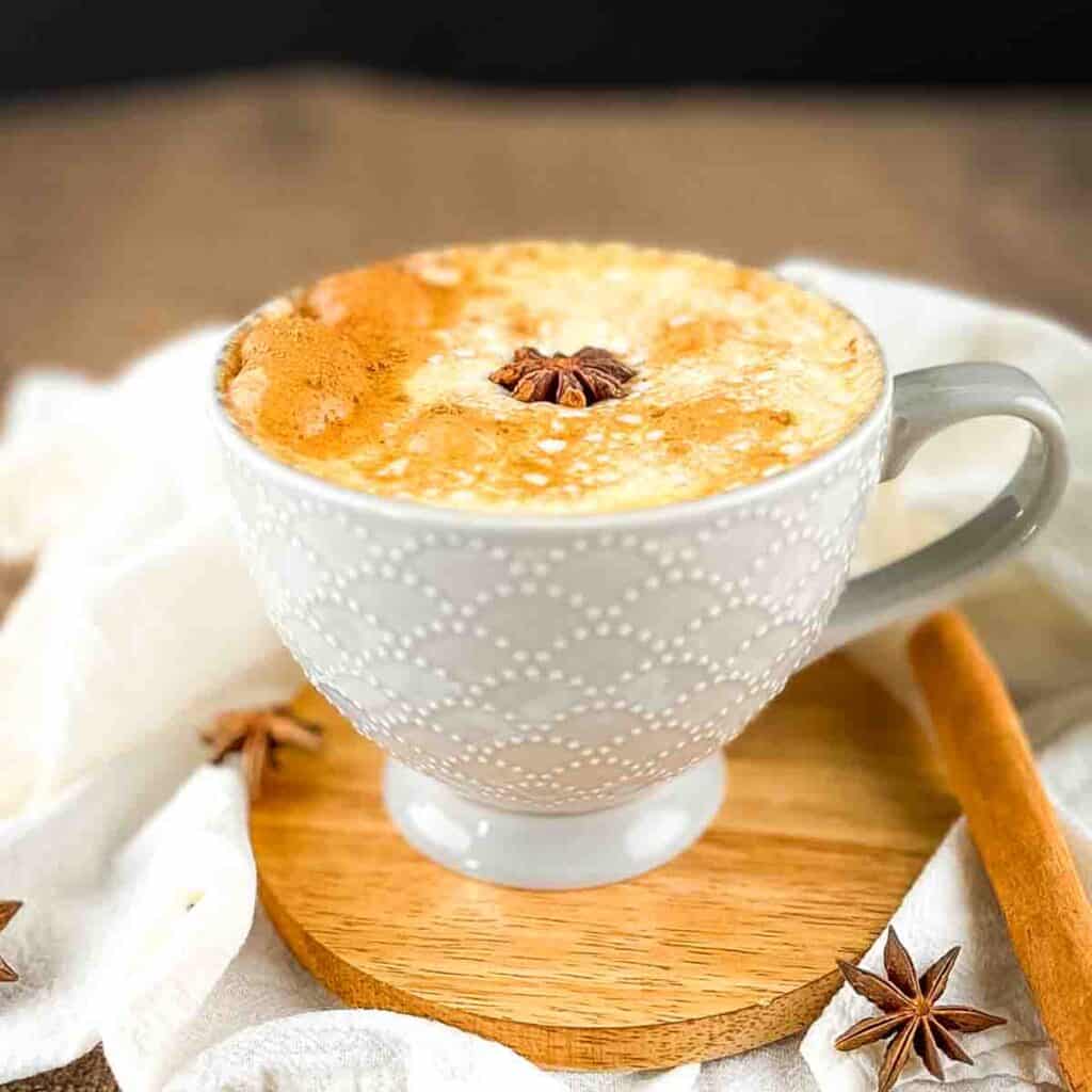A grey mug with pumpkin spice chai latte with a sprinkle of pumpkin pie spice and a star anise on top.