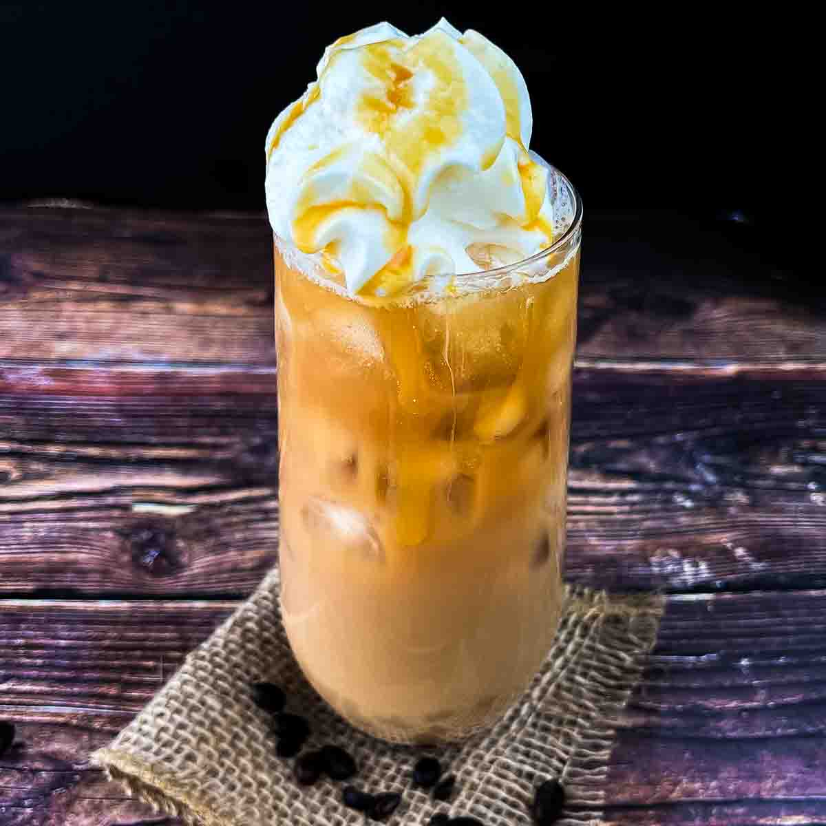 mcdonalds caramel iced coffee with whipcream on top drizzled with caramel sauce.