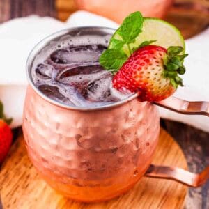 Strawberry moscow mule in a copper mug, garnished with a strawberry and fresh mint.