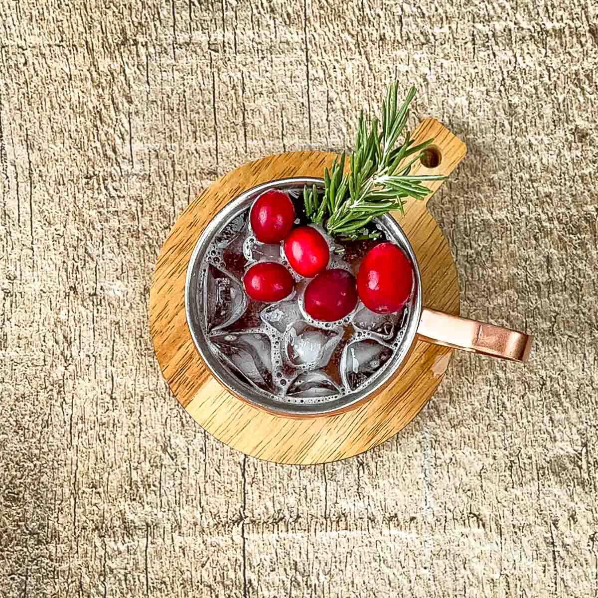 The cranberry mule garnished with fresh rosemary and fresh cranberries.
