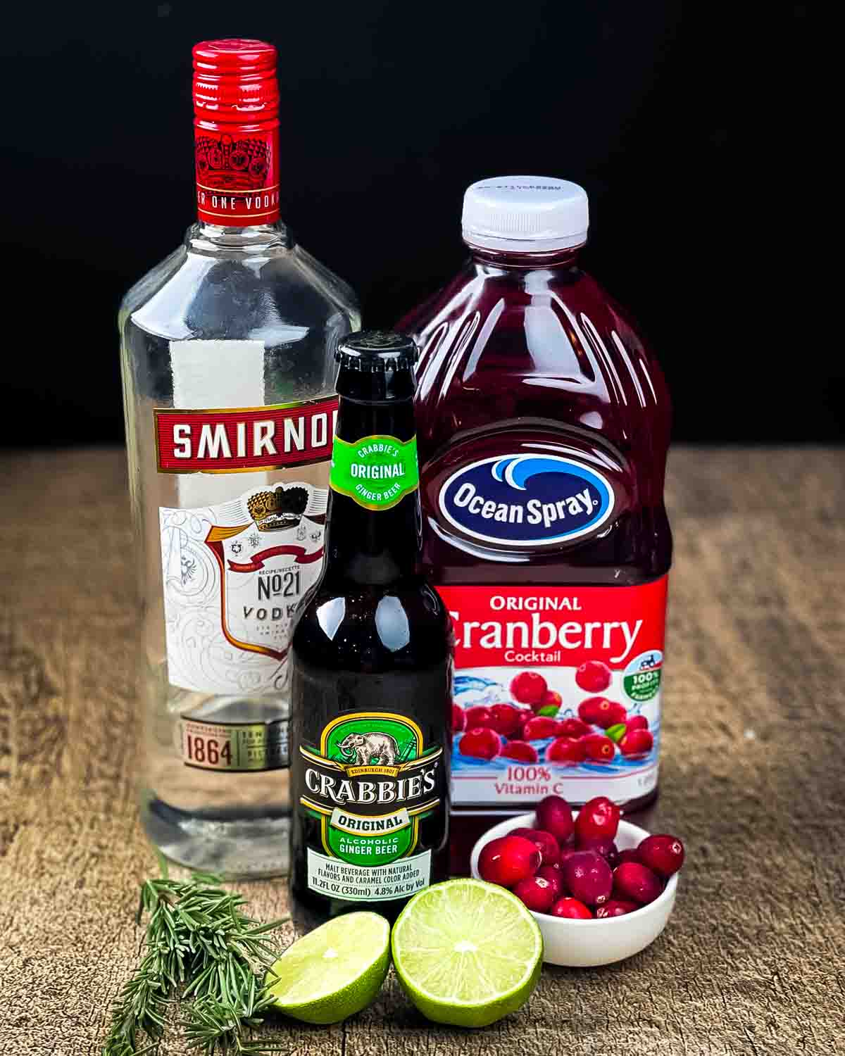 Ingredients for a cranberry Moscow mule on a wooden counter.