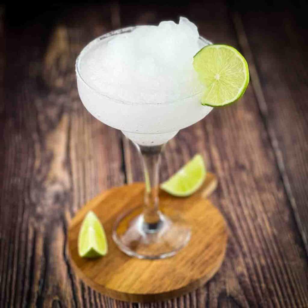 A margarita glass filled with a frozen margarita, garnished with a lime wheel.