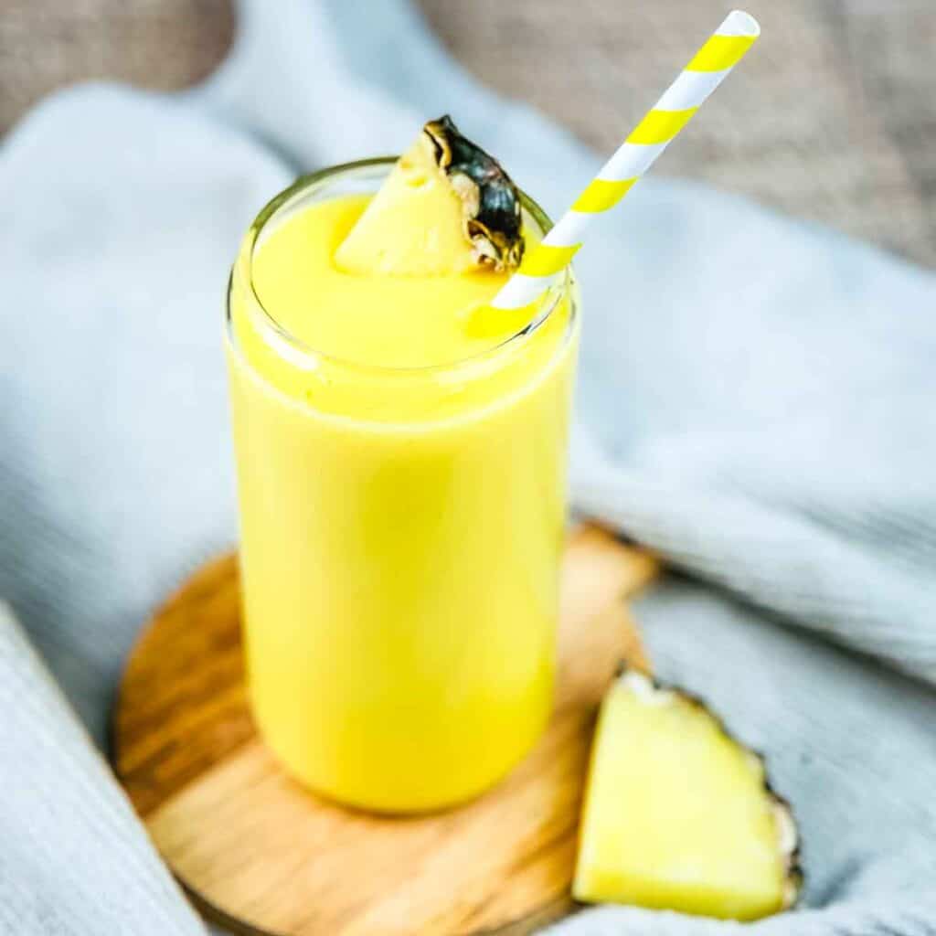 A tall glass of Tropical Smoothie Cafe Mango Magic smoothie, garnished with fresh pineapple.