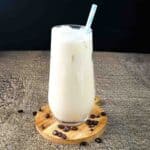 A tall glass of vanilla iced coffee with a green striped straw in it.