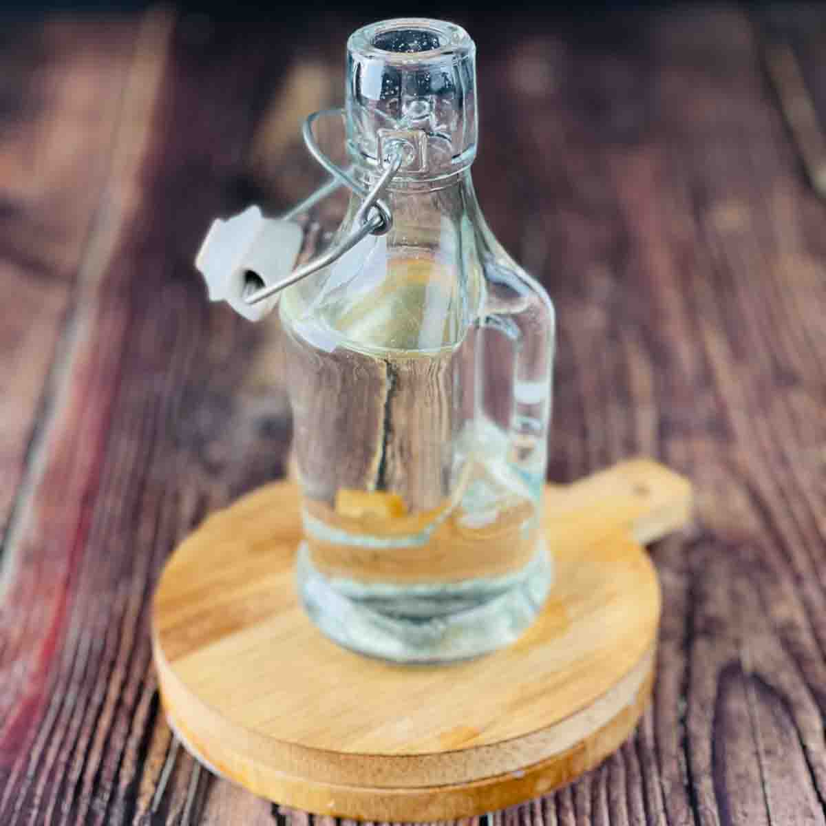 A bottle of homemade vanilla simple syrup on wooden coasters.