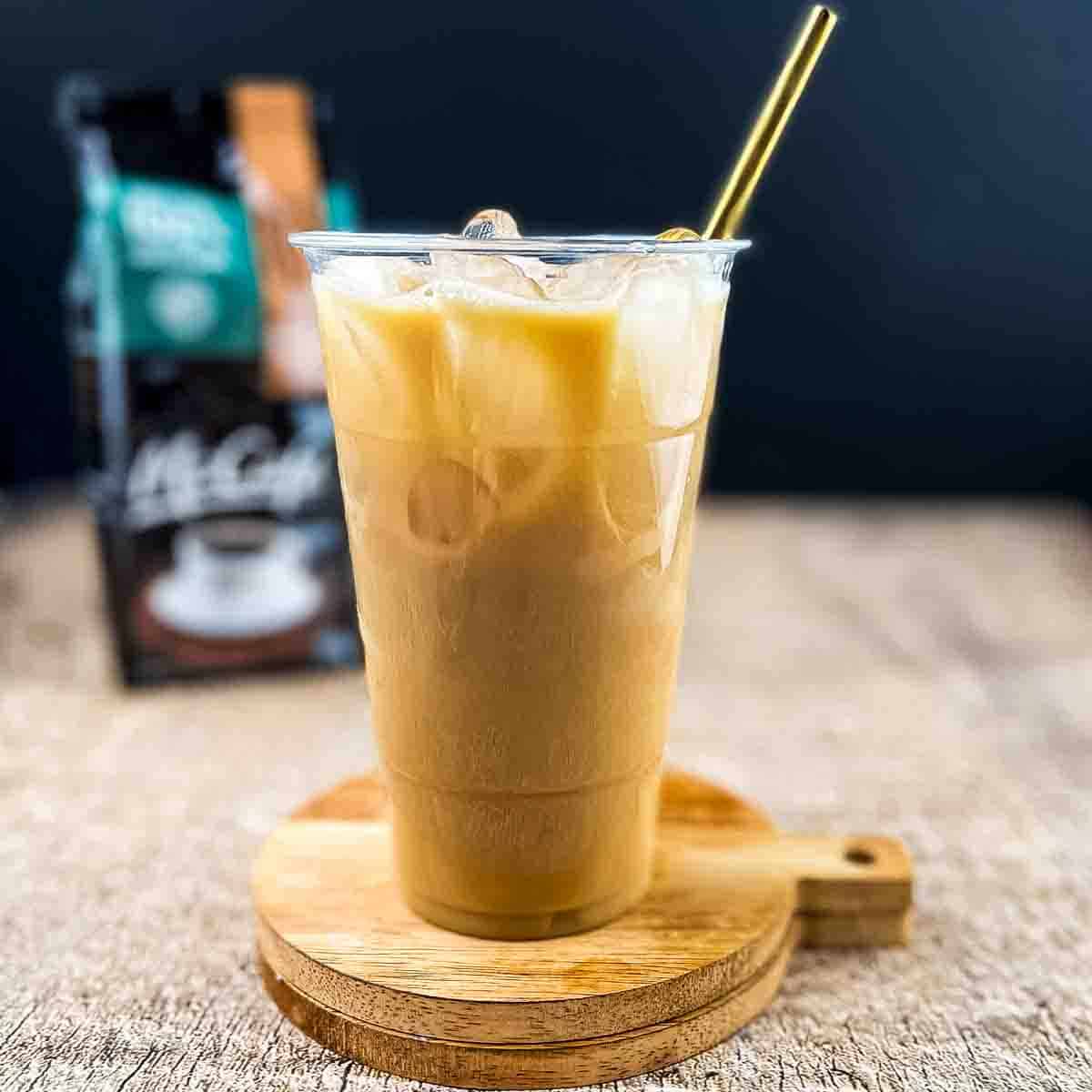 A tall glass of McDonalds iced coffee copycat recipe with a gold straw.