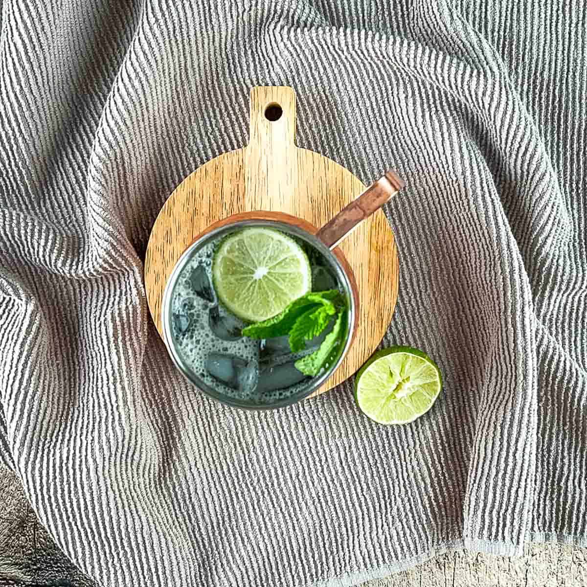 The moscow mule with white rum in a copper mug garnished with fresh mint and a lime wheel.