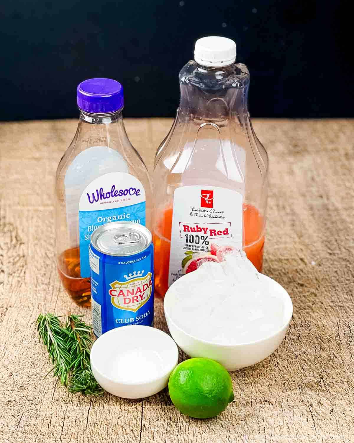Ingredients for Paloma mocktail placed on a wooden table.