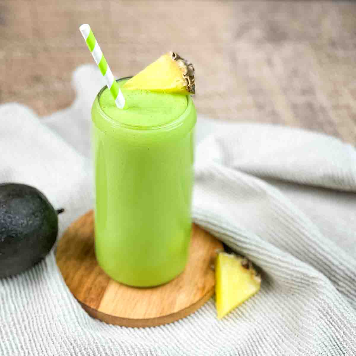 Thick and creamy smoothie in a tall glass with a green and white striped straw.