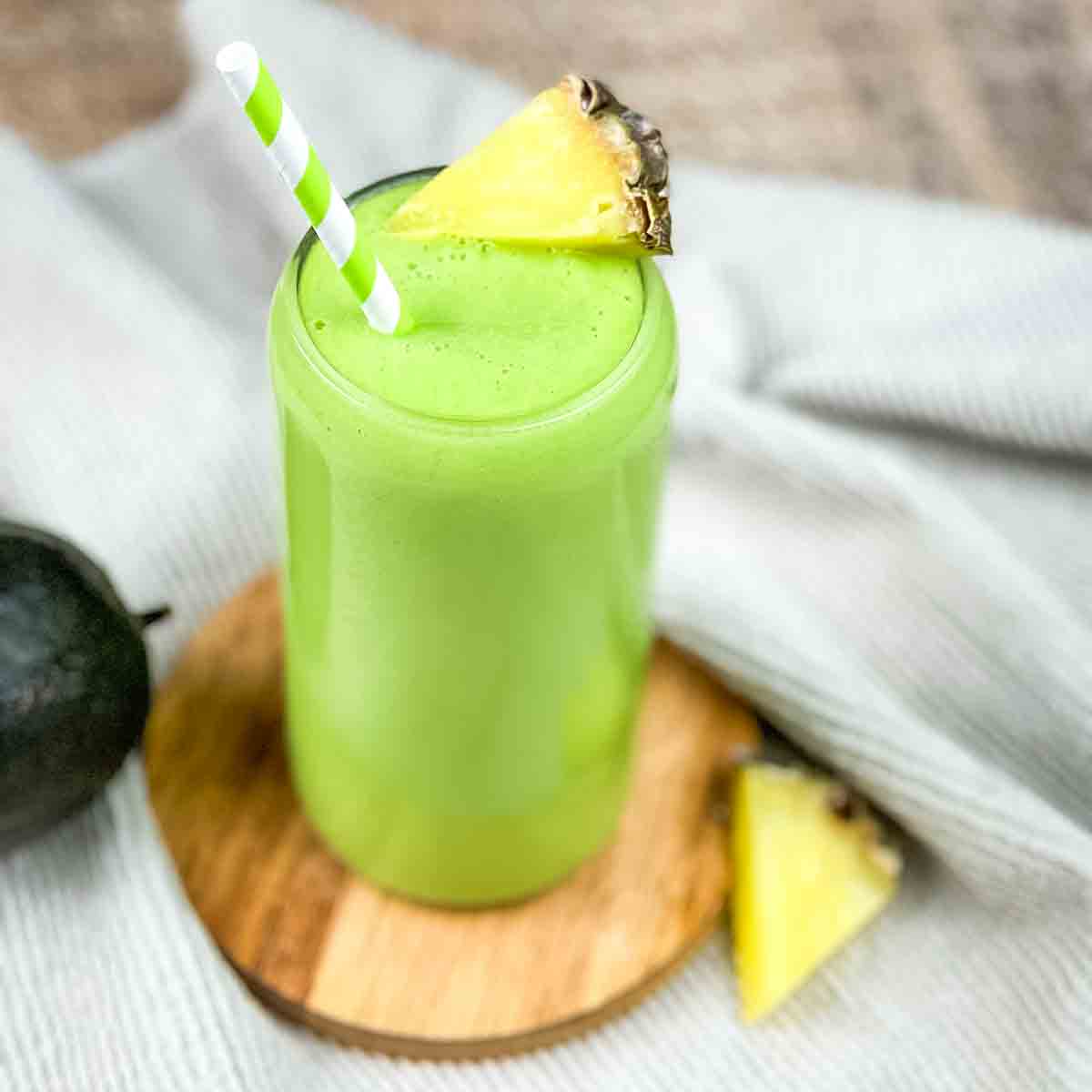 Avocolada smoothie in a tall glass garnished with a pineapple wedge.