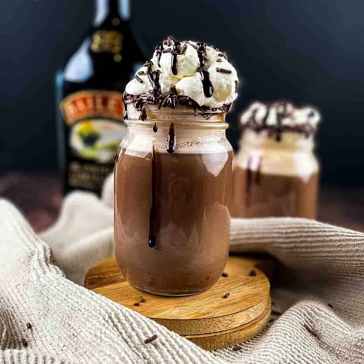 A glass mug filles with the adult hot chocolate topped with whipped cream.