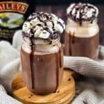 Two jars filled with dirty snowman cocktail and topped with whipped cream.