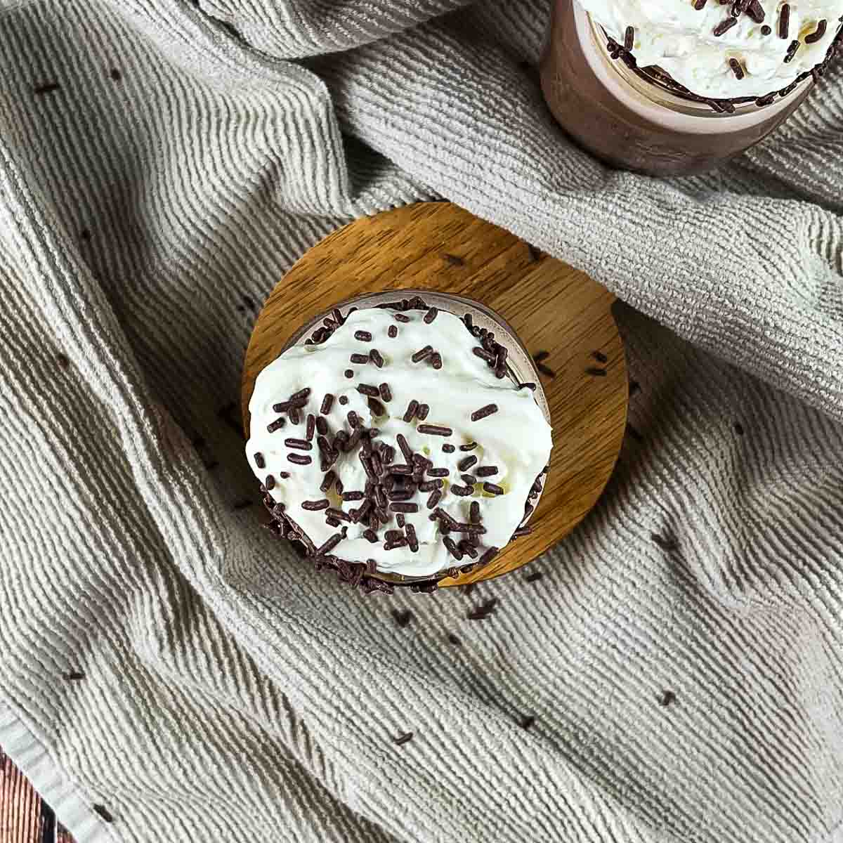 The mug topped with whipped cream and chocolate sprinkles.