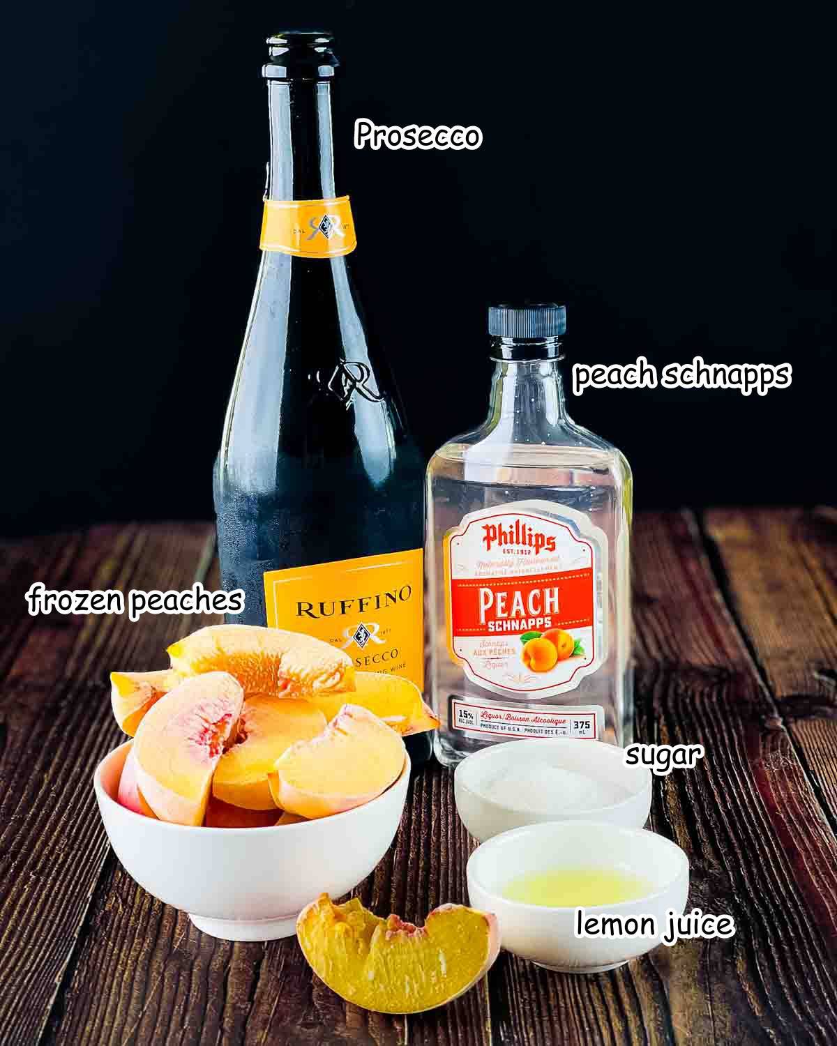 Ingredients for a frozen peach bellini placed on a wooden table.