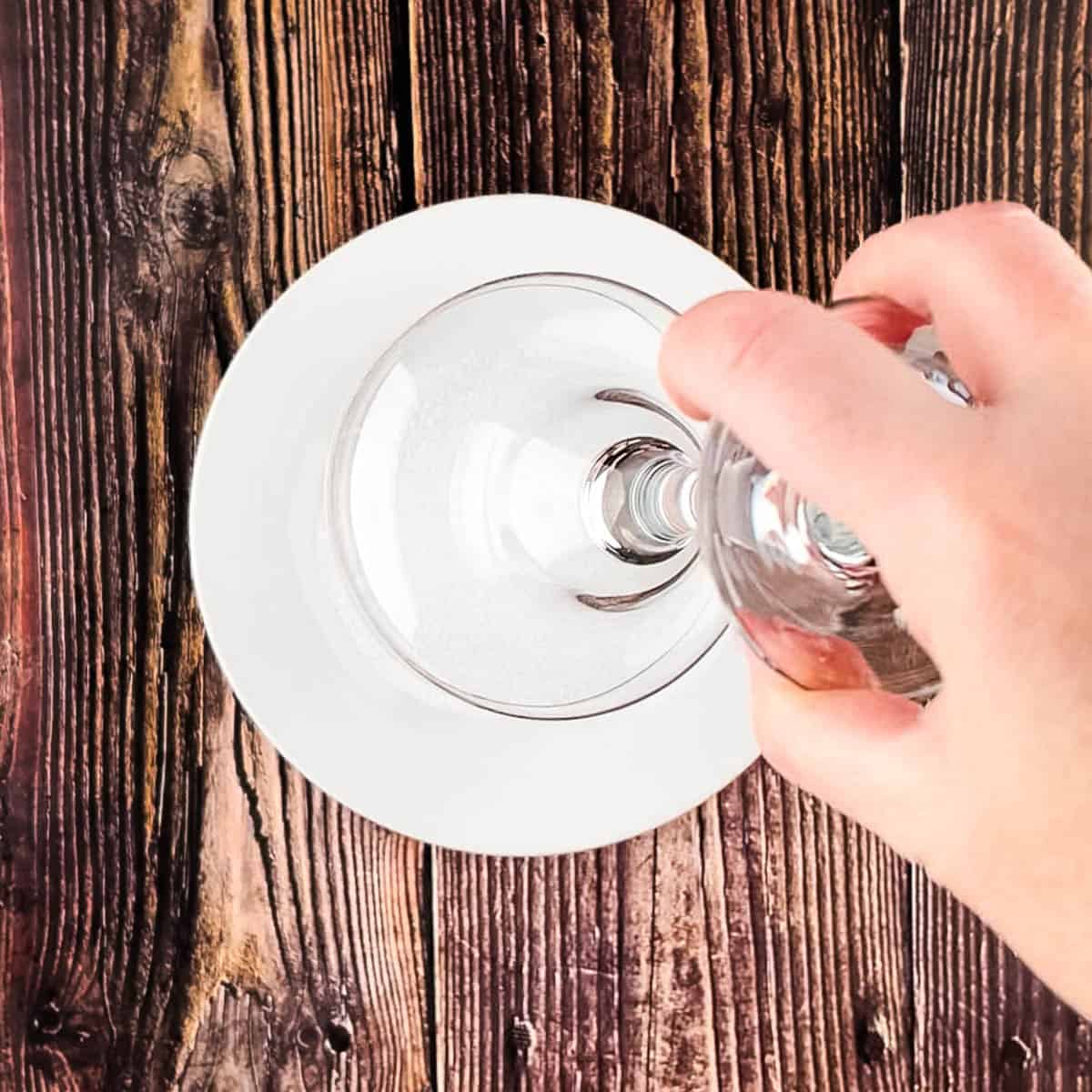 A cocktail glass rubbed with lime being dipped into coarse salt.