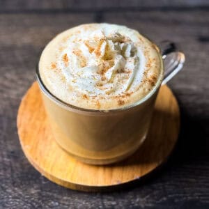 Eggnog chai latte topped with whipped cream and nutmeg in a glass mug, made with real eggnog and brewed chai tea.
