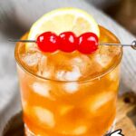 A cocktail glass filled with 3-ingredient rum sour garnished with lemon and three cherries.