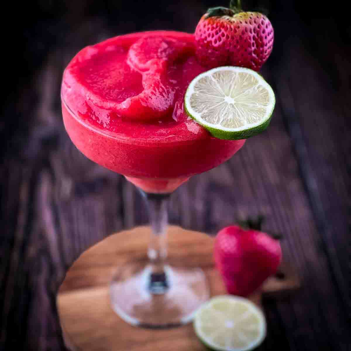 A tall glass filled with a frozen strawberry daiquiri, ready to be served.